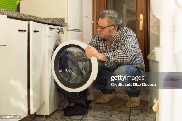 man crouching while loading clothes - bath mat stock pictures, royalty-free photos & images