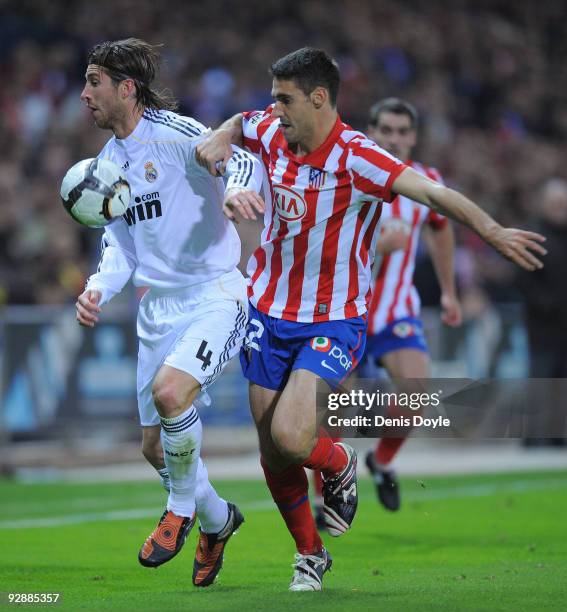 Pablo Ibanez of Atletico Madrid challenges Sergio Ramos of Real Madrid during the La Liga match between Atletico Madrid and Real Madrid at the...