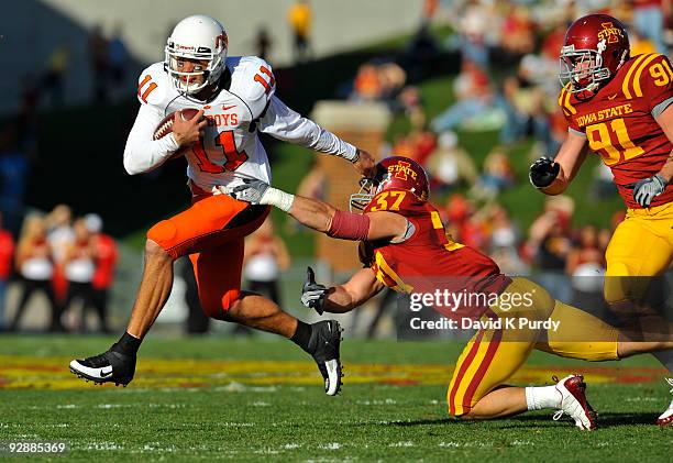 Quarterback Zac Robinson of the Oklahoma State Cowboys breaks away from defensive back Michael O'Connell, and linebacker Patrick Neal of the Iowa...