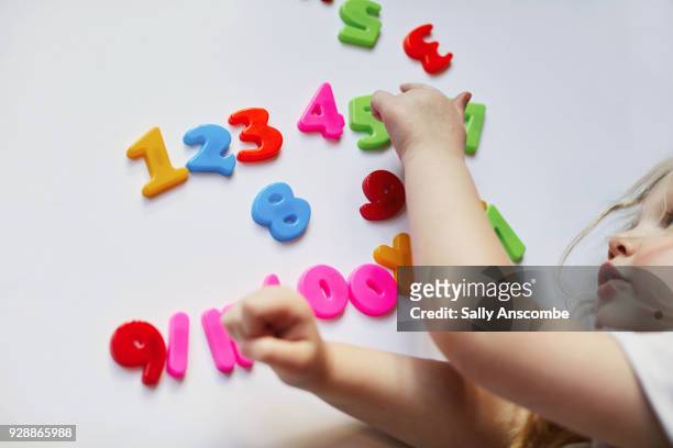 toddler playing with magnetic letters and numbers - bokstavsmagnet bildbanksfoton och bilder