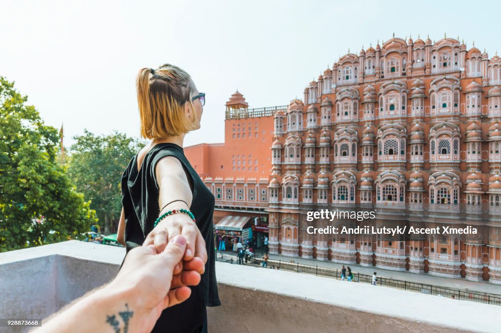 Young woman holds hand above Hawa Mahal