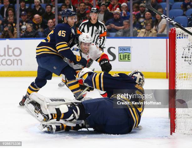 Chad Johnson of the Buffalo Sabres makes a save against Garnet Hathaway of the Calgary Flames as Brendan Guhle defends during the first period at...