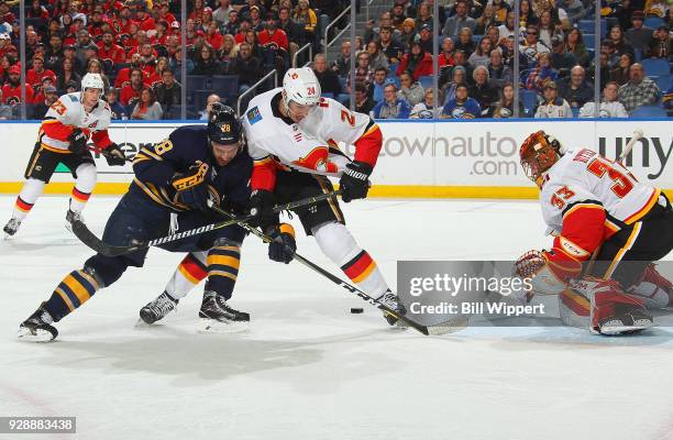 Zemgus Girgensons of the Buffalo Sabres is defended by Travis Hamonic and David Rittich of the Calgary Flames during an NHL game on March 7, 2018 at...