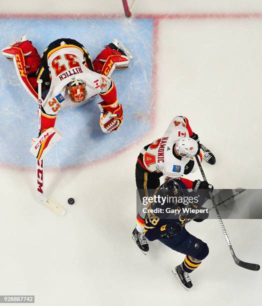 Zemgus Girgensons of the Buffalo Sabres is defended by David Rittich and Travis Hamonic of the Calgary Flames during an NHL game on March 7, 2018 at...