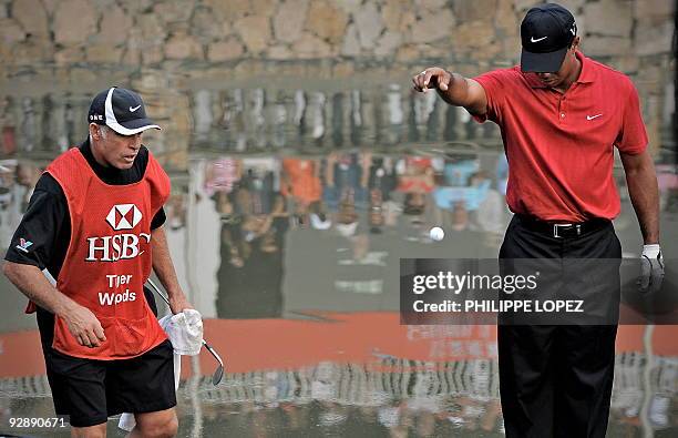 Golfer Tiger Woods drops the ball back to the green after it landed in the water on the 18th and last hole during the HSBC Champions golf tournament...