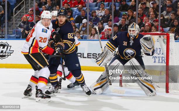 Curtis Lazar of the Calgary Flames battles for position with Nathan Beaulieu in front of goaltender Chad Johnson of the Buffalo Sabres during an NHL...