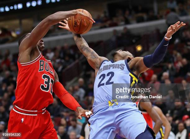 Kris Dunn of the Chicago Bulls blocks a shot by Xavier Rathan-Mayes of the Memphis Grizzlies but is called for a foul at the United Center on March...