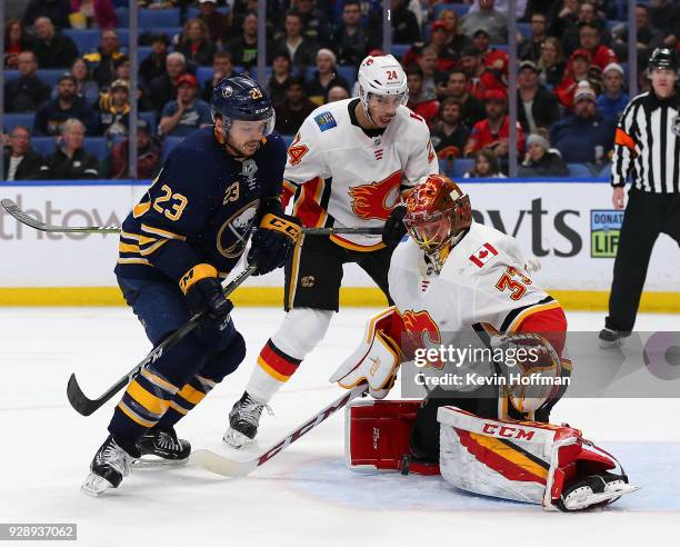 David Rittich of the Calgary Flames makes the save against Sam Reinhart of the Buffalo Sabres as Travis Hamonic looks on during the second period at...