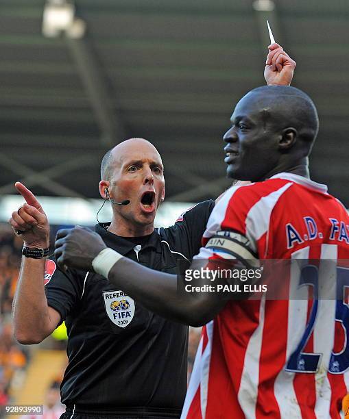 Referee Mike Dean books Stoke City's Senegalese player Abdoulaye Faye during the English Premier League football match between Hull City and Stoke...