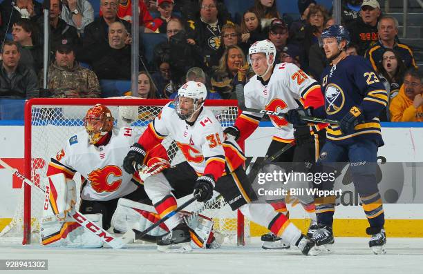 David Rittich, Troy Brouwer, and Michael Stone of the Calgary Flames defend against Sam Reinhart of the Buffalo Sabres during an NHL game on March 7,...