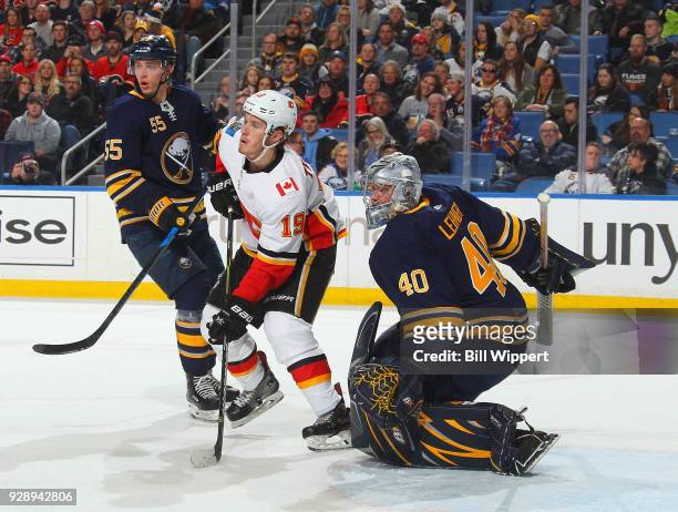 Matthew Tkachuk of the Calgary Flames battles for position in front of Robin Lehner and Rasmus Ristolainen of the Buffalo Sabres during an NHL game...