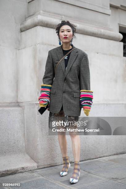 Guest is seen on the street attending Jourden during Paris Women's Fashion Week A/W 2018 wearing a grey tweed blazer with rainbow arm warmers, white...