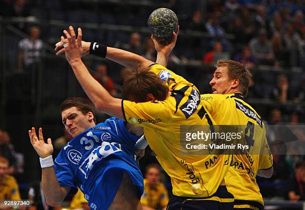Ole Rahmel of Gummersbach shoots as Siarhei Harbok and Oliver Roggisch of Loewen defend during the Toyota Handball Bundesliga game between VfL...