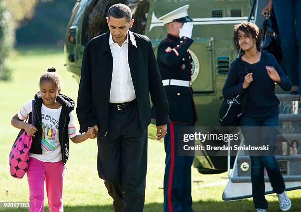 President Barack Obama holds the hand of his daughter Sasha as daughter Malia walks off Marine One to the White House November 8, 2009 in Washington,...