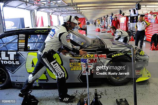 Chad Knaus, crew chief for Jimmie Johnson, driver of the Lowe's Chevrolet, pushes the car into the garage after being involved in a crash with Sam...