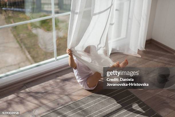 baby playing with curtain - kid hide and seek stock pictures, royalty-free photos & images