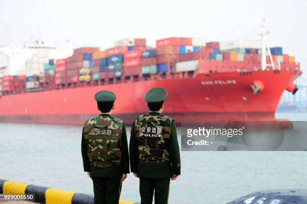 Chinese police officers watch a cargo ship at a port in Qingdao in China's eastern Shandong province on March 8, 2018. China's trade surplus with the...