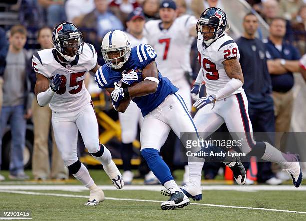 Pierre Garcon of the Indianapolis Colts runs with the ball while defended by Jacques Reeves and Glover Quin of the Houston Texans during the NFL game...