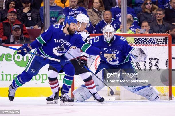 Vancouver Canucks Goalie Jacob Markstrom tracks the puck as Defenceman Erik Gudbranson defends against Arizona Coyotes Winger Nick Cousins during...