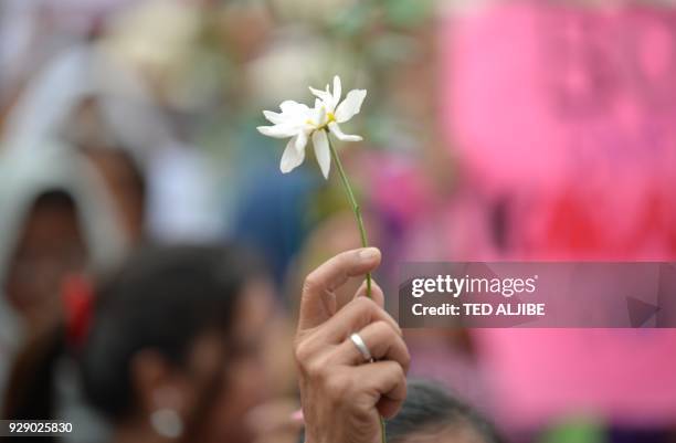 Woman protester holds a flower during a rally to celebrate International Women's Day in Manila on March 8, 2018. The protesters including the...