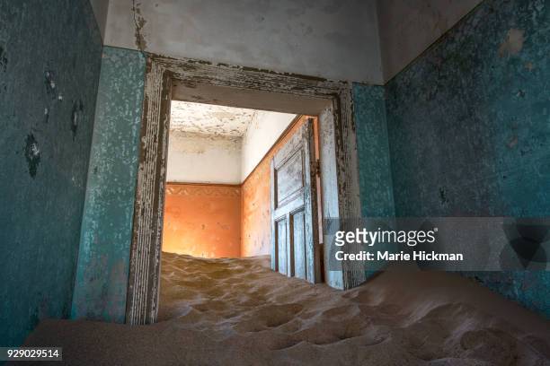 door, stuck in the sand inside a home in kolmanskop, an abandoned diamond mining town, a tourist destination, in namibia, africa. - marie hickman stock-fotos und bilder