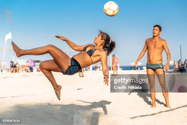 mulher brasileira, pulando e chutando a bola na praia no brasil - beach volleyball - fotografias e filmes do acervo