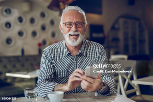senior man using smart phone in cafe - senior men cafe stock pictures, royalty-free photos & images