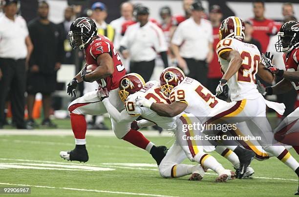 Michael Turner of the Atlanta Falcons carries the ball against LaRon Landry and London Fletcher of the Washington Redskins at the Georgia Dome on...