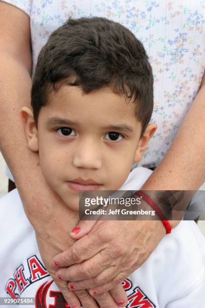 Grandmother's hands wrapped around a boy at the Tres Reyes Magos Three Kings Parade.