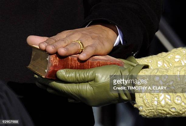 Barack Obama's hand lies on a bible as he is sworn in as the 44th US president by Supreme Court Chief Justice John Roberts in front of the Capitol in...