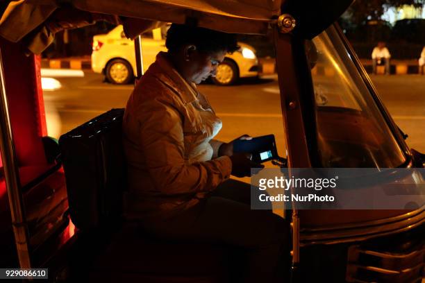 Sunita Choudhary - North India's first auto-rickshaw driver - checks her phone while waiting for customers in Central Delhi on 6th March, 2018....