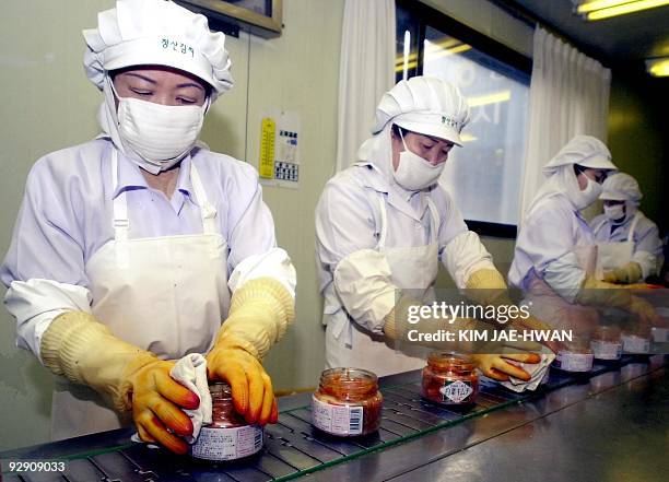 Jars of Korean kimchi, Chinese cabbage seasoned with natural ingredients including red pepper, garlic and ginger are lined up and being cleaned by...