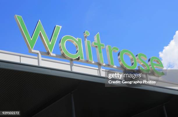 Green Waitrose supermarket shop sign against blue sky, Ipswich, Suffolk, England, UK.