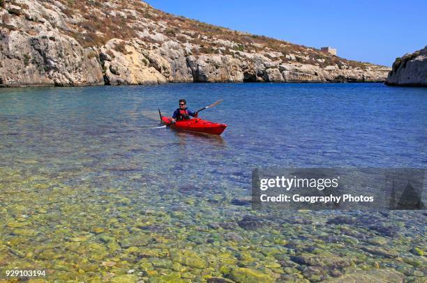 Kayaking shoreline clear blue sea water, Mgarr ix-Xini coastal inlet, island of Gozo, Malta.
