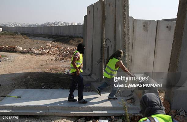 Palestinian and international peace activists pull down a concrete block, part of Israel's controversial separation barrier, during a protest in the...