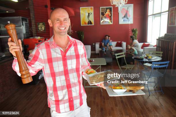 The manager of Le Petit Paris Café serving plates of food.