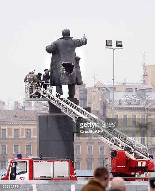 Russian forensic experts examine the holes from a bomb blast in a monument of Soviet Union founder Vladimir Lenin in St. Petersburg on April 1, 2009....