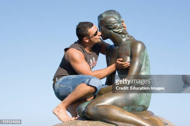 Tourist kissing The Little Mermaid, Copenhagen Denmark, Man kissing statue.
