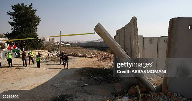 Local and international peace activists pull down a concrete block, part of Israel's controversial separation barrier, during a protest in the...