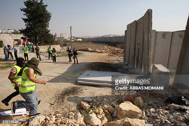 Local and international peace activists pull down a concrete block, part of Israel's controversial separation barrier, during a protest in the...
