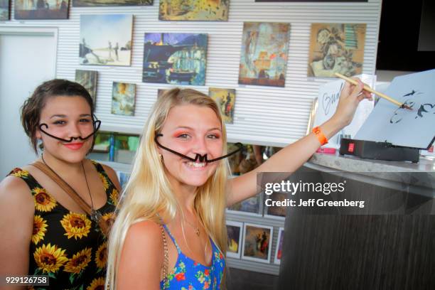 Two girls wearing pipe cleaner mustaches inside the gift shop at the Salvador Dali Museum.