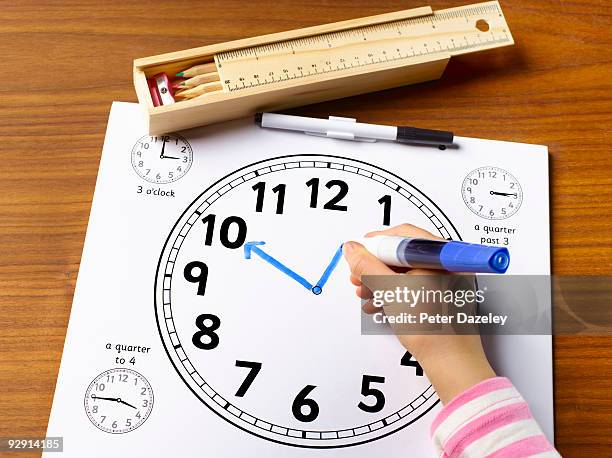 school child age 4 - 7 learning to tell the time. - etui stockfoto's en -beelden