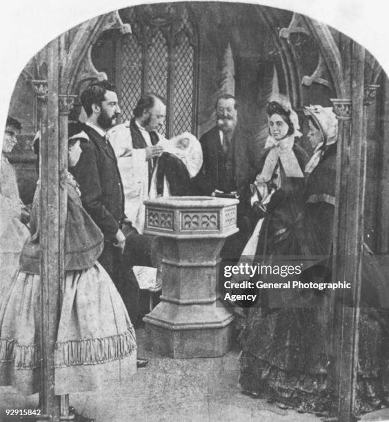 Victorian christening ceremony with parents and godparents at the baptism font, circa 1860.