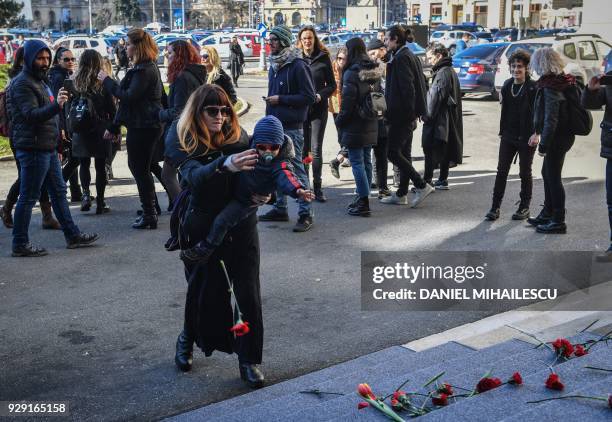 Woman carrying a child throws flowers on the steps of the Romanian Ministry of Interior during a protest against domestic violence on the...