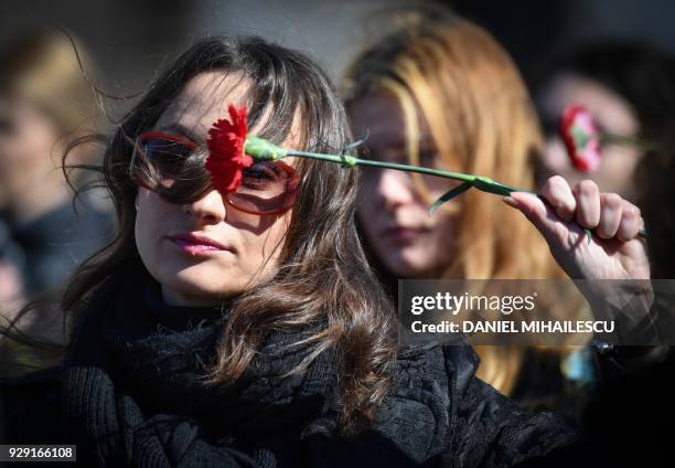 Women holds a flower as she protests against domestic violence in front of the Romanian Ministry of Interior in Bucharest on March 8 the...