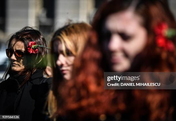 Women holds a flower as she protests against domestic violence in front of the Romanian Ministry of Interior in Bucharest on March 8 the...