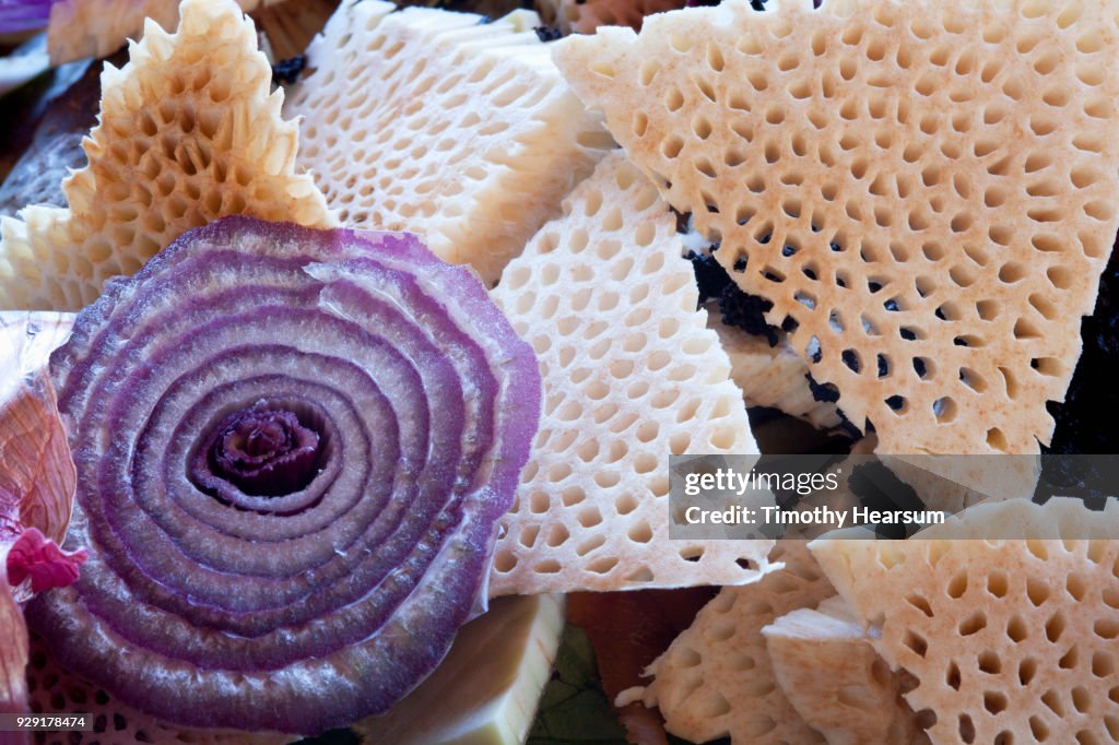 Close-up of cross section of a purple onion surrounded by triangular slices of breadfruit