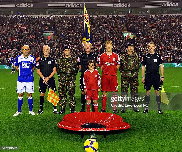 Two soldiers stand alongside captains Stephen Carr of Birmingham City and Dirk Kuyt of Liverpool and match officials after placing a giant poppy on...