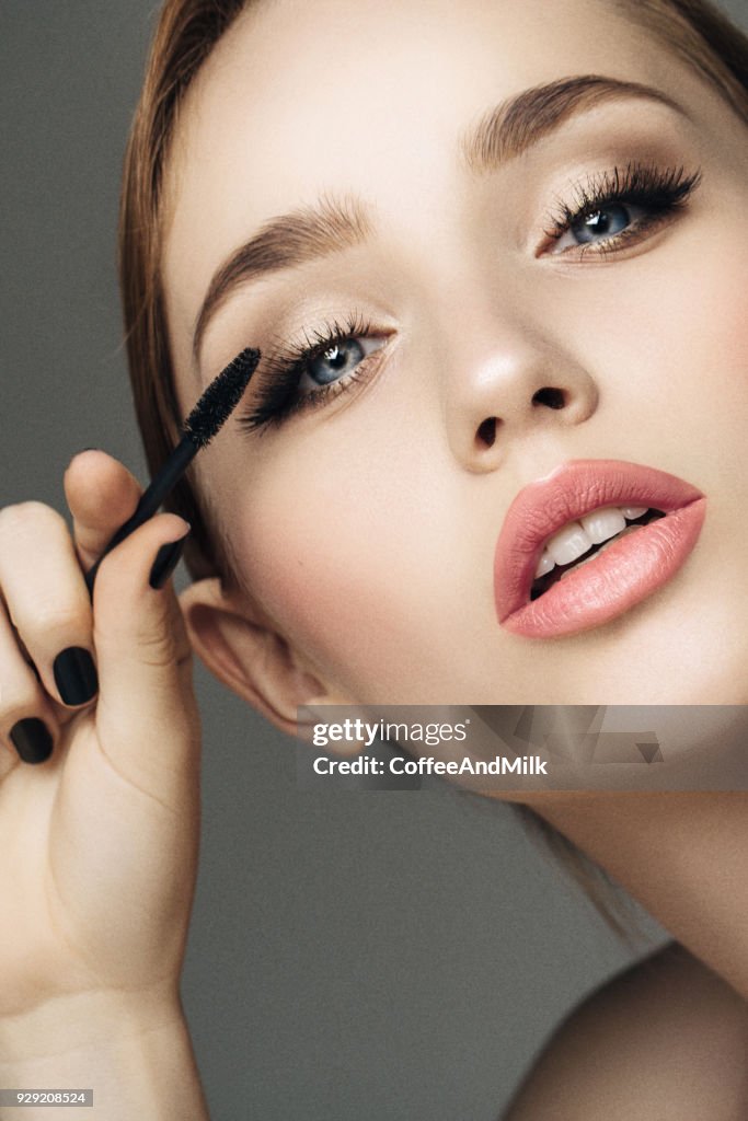 Beautiful woman applying mascara