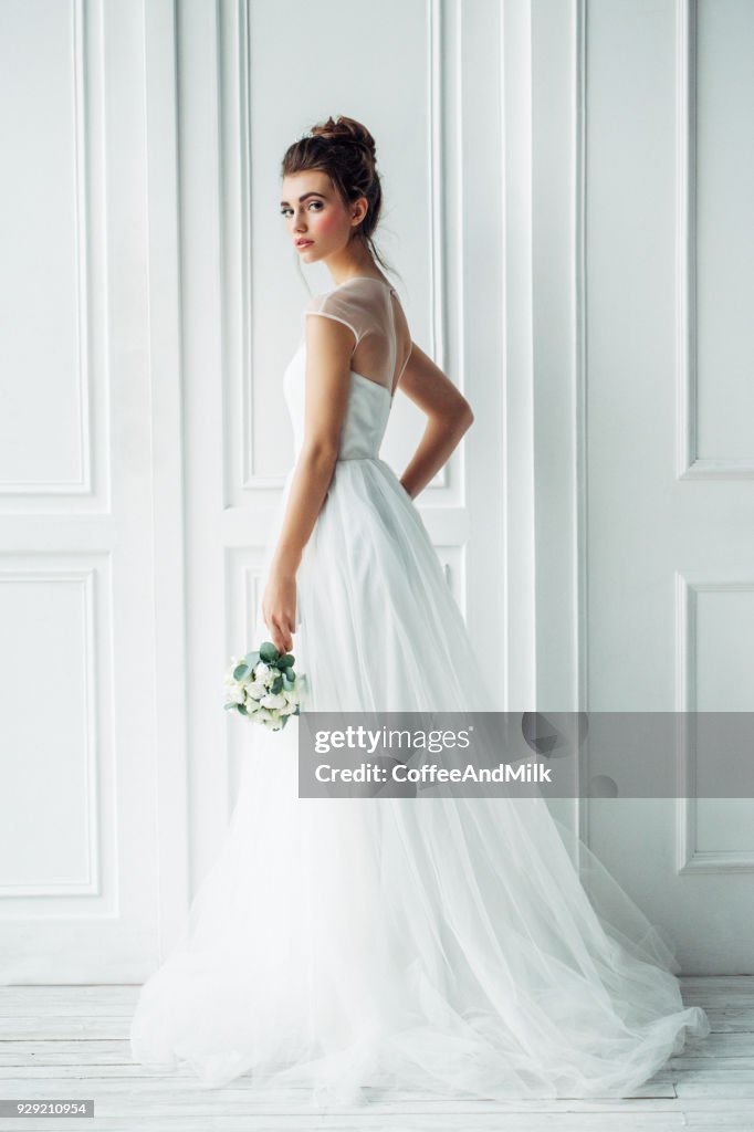 Bella donna bruna come sposa con bouquet di nozze
